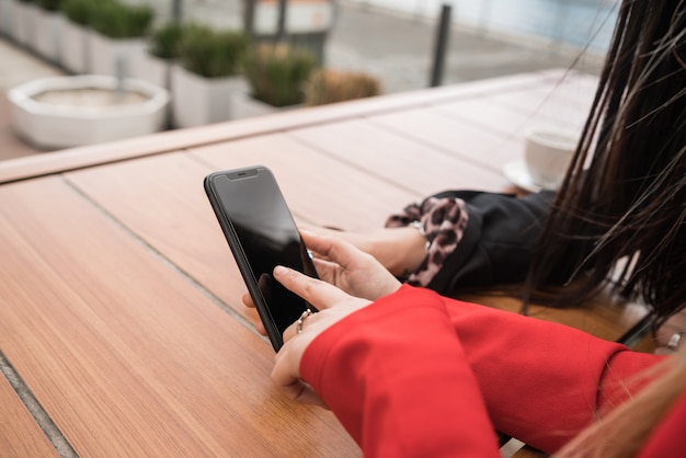 Two friends using their mobile phone while sitting at coffee shop.