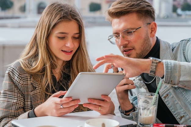 Foto due amici che lavorano in un bar con i loro computer