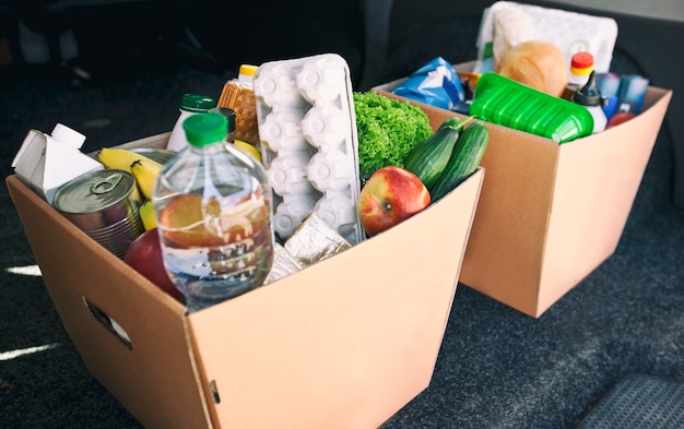 Two full cardboard eco boxes with products from grocery store in the car