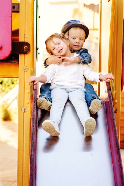 Due bambini divertenti sullo scivolo del parco giochi