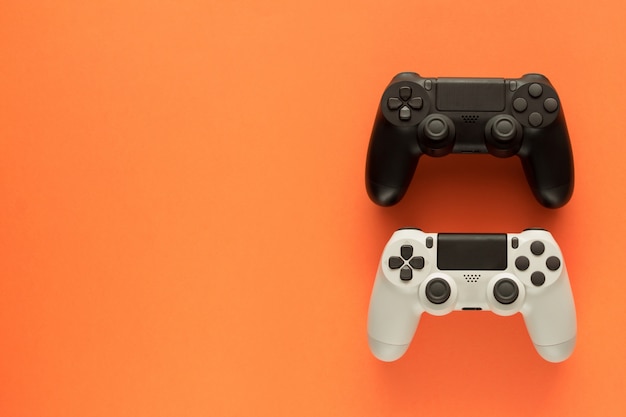 two gamepads on a orange table and copy space