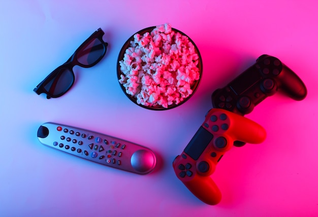 Фото Два геймпада, пульт от телевизора, 3d-очки и миска с попкорном