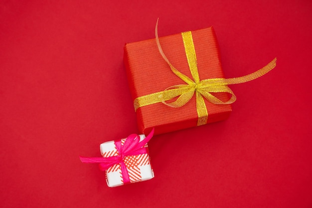 활이 있는 두 개의 선물 상자. 빨간색 배경에 크리스마스 선물