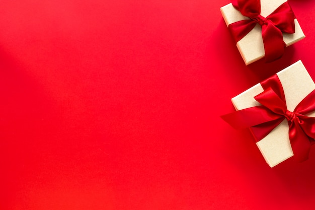 Two gift boxes with a red bow on a red, top view with copy space