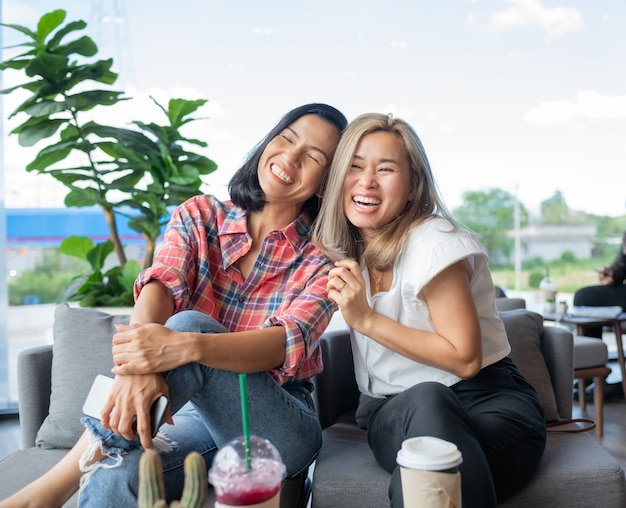 Two girl friends laughing at a cafe.