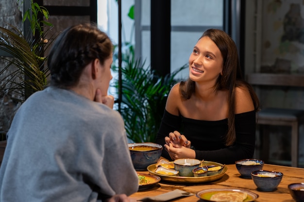 Two girl-friends talk and eat in a modern cafe