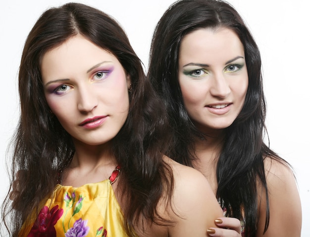 Two girl friends together smiling.Studio shot.