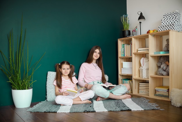 A two girl in medical mask siting on wood floor and reading a books during quarantine