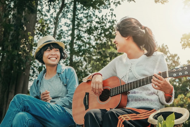 ギターを弾く2人の女の子と自然の中で幸せと笑顔