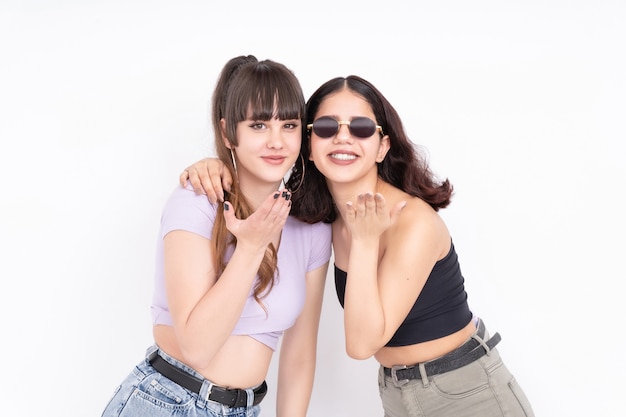 Due amiche che salta un bacio alla telecamera divertendosi su bianco