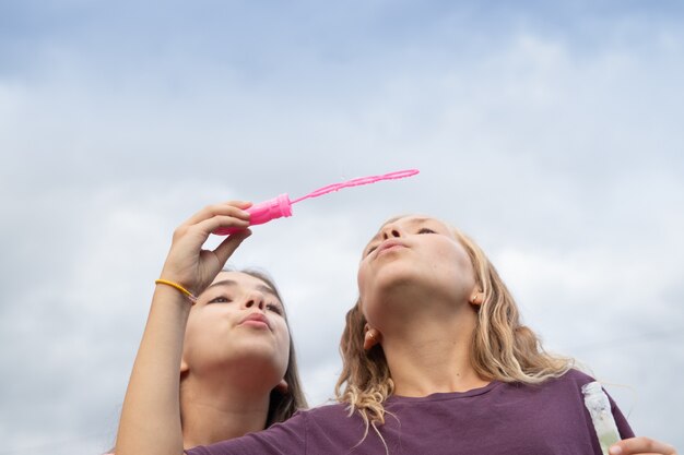 Foto due amiche che soffiano bolle di sapone: tempo e amicizia spensierati e divertenti