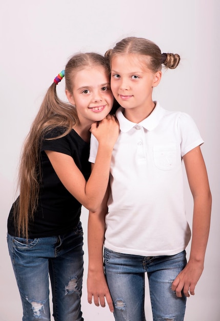 Due amiche ragazze felici carine in maglietta bianca e nera su sfondo bianco