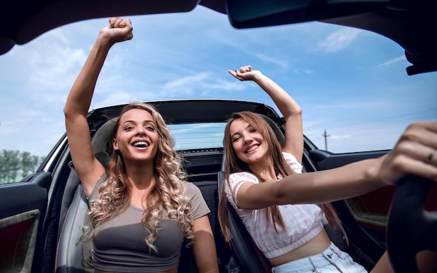 Two girlfriends enjoying a trip in a convertible car