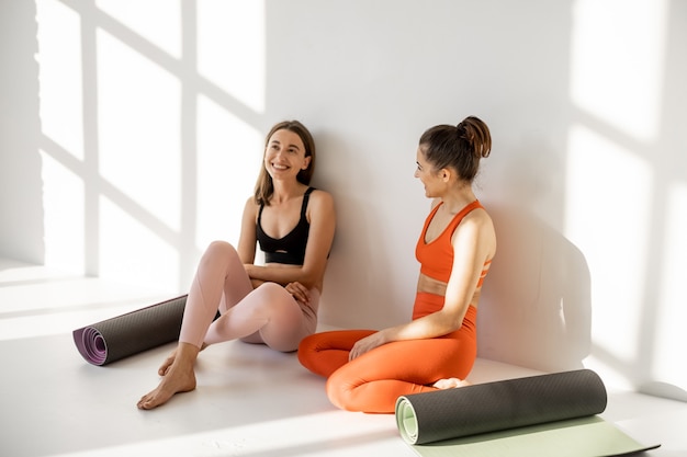 Photo two girlfriends talk on a yoga break indoors