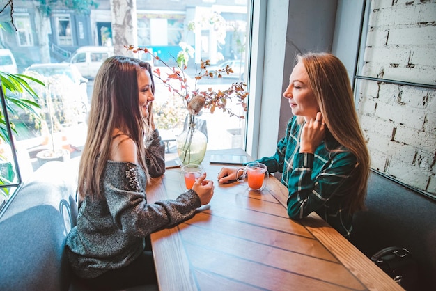 お茶会を飲みながらカフェで話している 2 人のガール フレンド