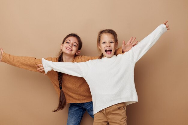 Two girlfriends together kids fun studio beige background