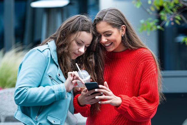 Two girlfriends use a smartphone laugh and talk technology concept with always connected milenials