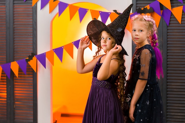 Two girls against a garland of orange and purple flags that hang on the wall