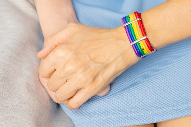 Two girls are holding hands, on one hand there is LGBT bracelet. The concept of love, sexual tolerance, homosexuality.