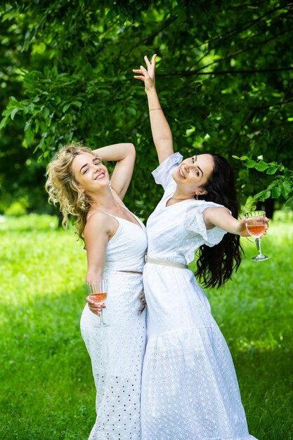 Foto due ragazze si riposano nel parco sedute su una coperta da picnic amici sta facendo picnic all'aperto