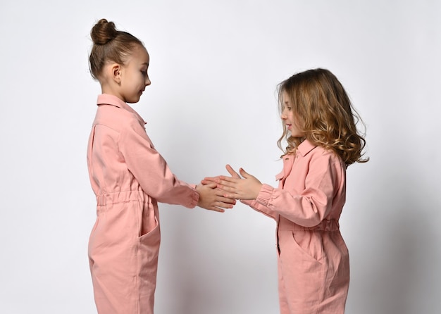 Photo two girls are sisters which are against each other and play with their hands the children are