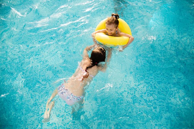 Two girls bathes in the pool in blue goggles for swimming.