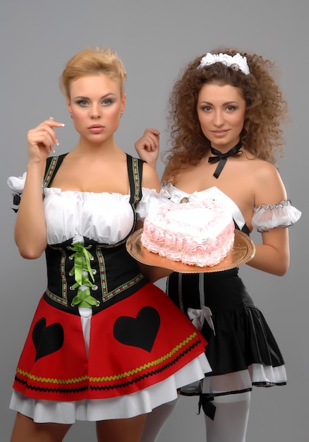 Two girls in beautiful dresses in gray and cake