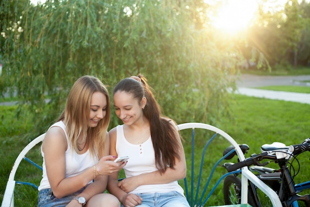 ベンチでの二人の少女は、自分の携帯電話を見て