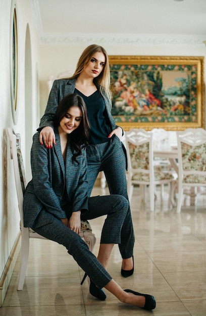 Two girls in black jackets on beige background