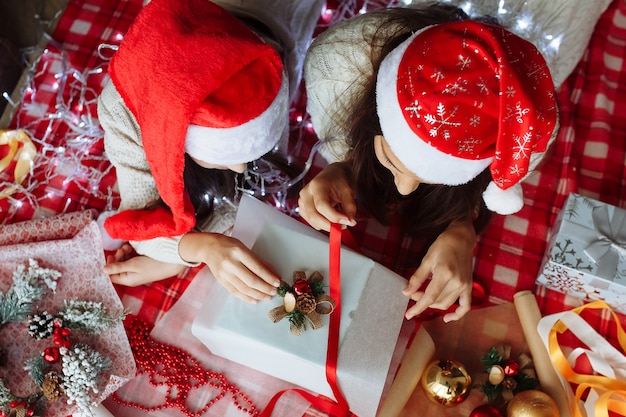 Two girls in christmas hats packing christmas gifts