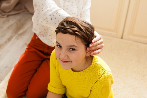 Two girls doing hair sitting on the floor in the room