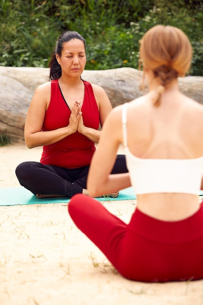 Две девушки занимаются йогой и медитацией на открытом воздухе, занимаются парными занятиями йогой, здоровым образом жизни, медитацией и благополучием.