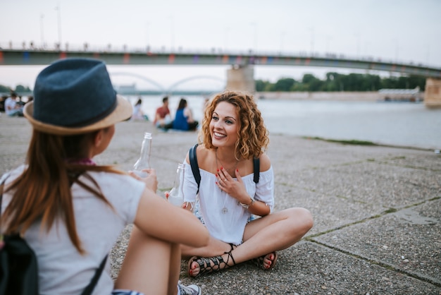 Photo two girls drinking and having fun in the summer near the river.