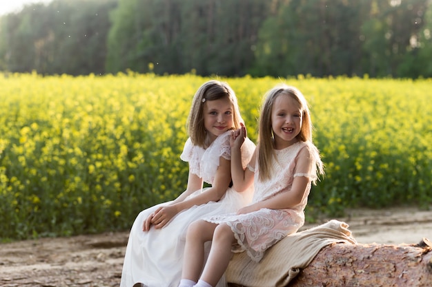 Photo two girls in a field of rapeseed in summer