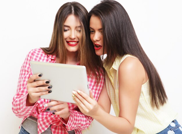 Two girls friends taking selfie with digital tablet over white background