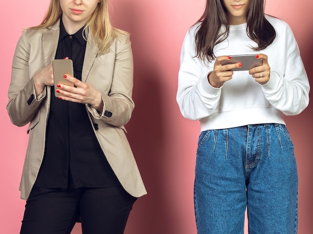 두 여자, 모바일 스마트폰을 사용하는 친구. 십대들은 새로운 기술 트렌드에 중독됩니다. 확대.