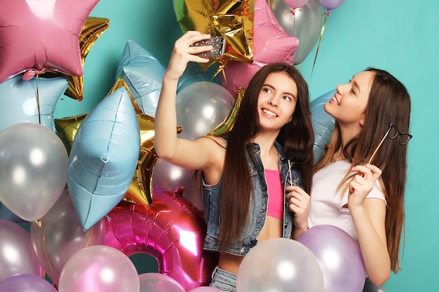 Two girls friends with colorfoul balloons make selfie on a ph