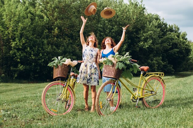 Two girls friends with retro bikes are relaxing in nature