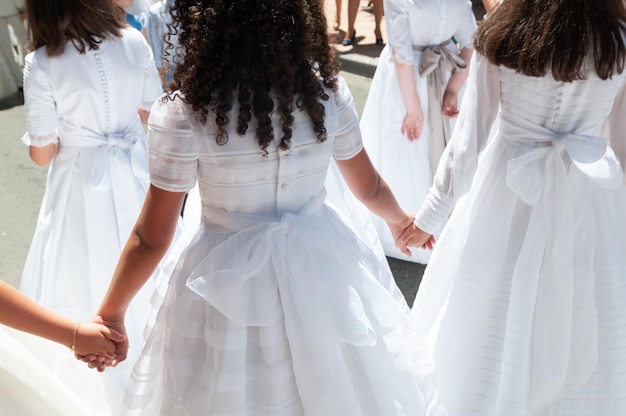 Two girls holding hands at their first communion in white dresses