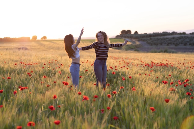 Two girls jumping at sunset in the poppy field