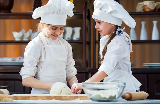 Two girls make flour dough.