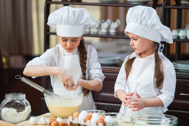 Two girls make flour dough.