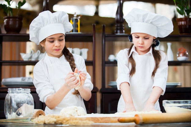 Two girls make flour dough.