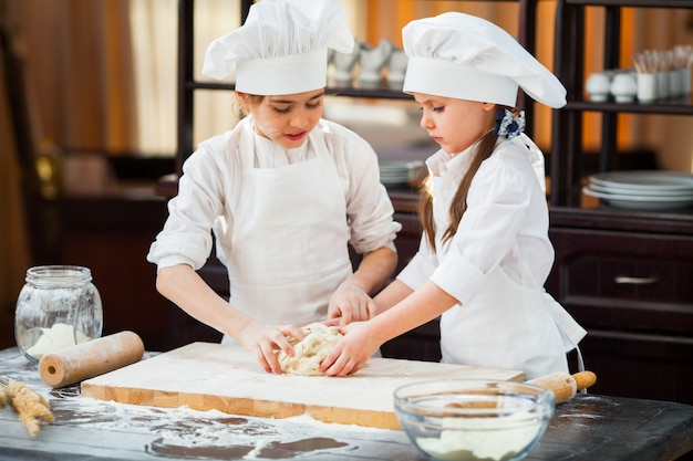 Two girls make flour dough.