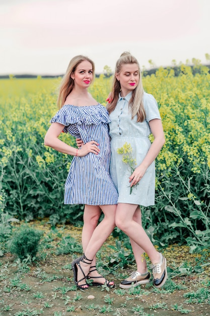 Two girls models posing together on camera in the rapeseed field