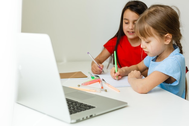 Due ragazze, la più grande e la più giovane, sono impegnate a un tavolo su un laptop.