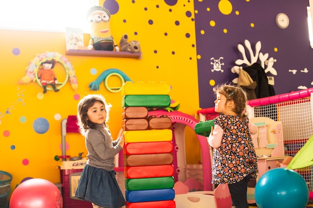 Two girls play with big bricks in playroom