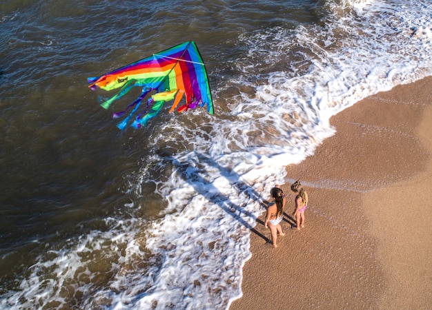 Two girls play with a kite by the sea