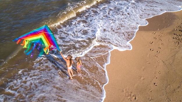 Two girls play with a kite by the sea