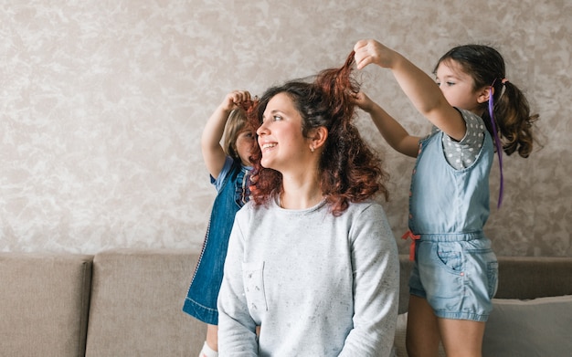 Two girls play with their mother, do her hair, comb her hair. happy and cheerful mom